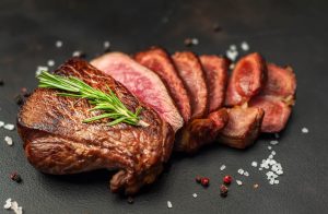Beef steak, herbs and spices on a stone background